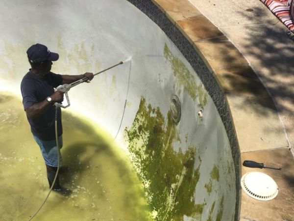 image of technician using pressure washing equipment to clean the pool surface